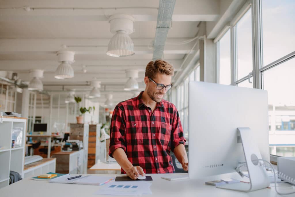 employé de bureau travaille debout sur un bureau à hauteur réglable